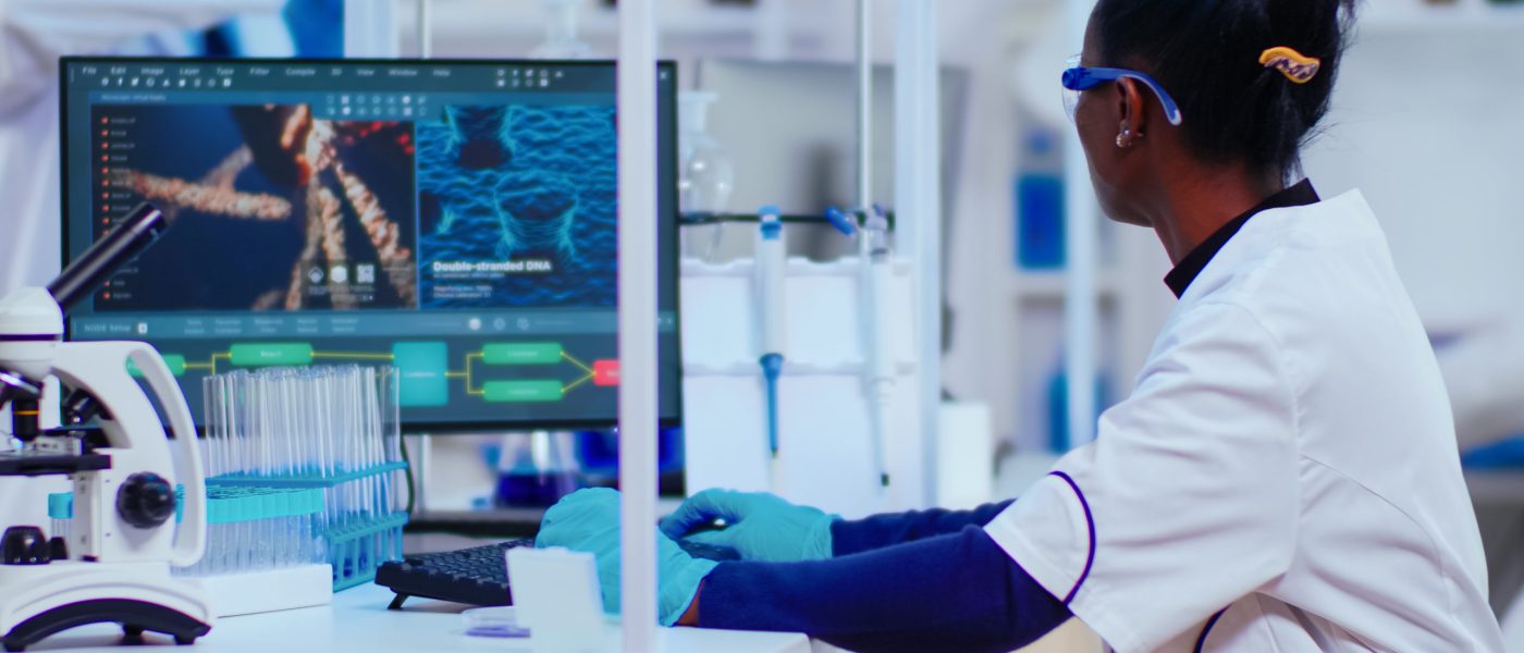 African woman biochemist researcher checking manifestations of vaccine working in modern equipped laboratory. Multiethnic doctors examining virus evolution using high tech researching diagnosis